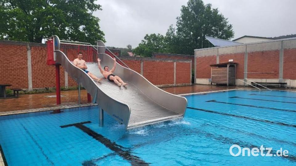 Bürgermeister Rudolf Teplitzky und Bademeister Reinhard Klein (von links) rutschen zur Saisoneröffnung ins 23 Grad warme Wasser. Bild: wel