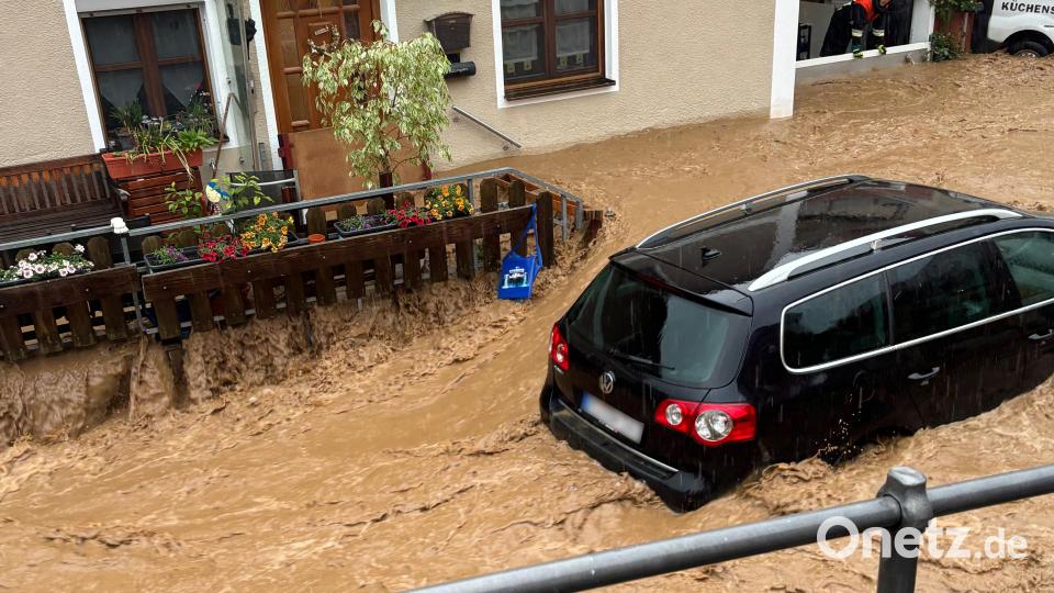 Ein Auto treibt nach starkem Regen in einer Straße in Kastl im Wasser. Bild: Haubner/Vifogra/dpa