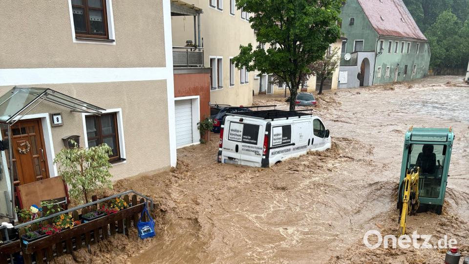 Ein Auto treibt nach starkem Regen in einer Straße in Kastl im Wasser. Bild: Haubner/vifogra/dpa
