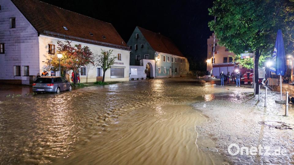 Wassermassen fließen nach starkem Regen aus dem Fluss Lauterach über den Marktplatz in der Gemeinde Kastl. Bild: Daniel Karmann/dpa