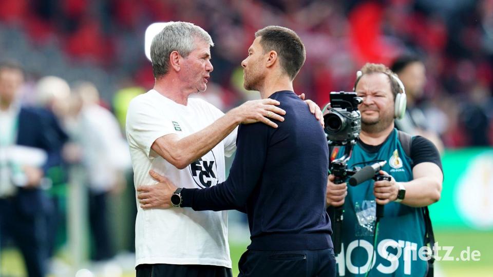 Kaiserslauterns Trainer Friedhelm Funkel (l) und Bayer-Coach Xabi Alonso begrüßen sich vor der Partie. Bild: Uwe Anspach/dpa
