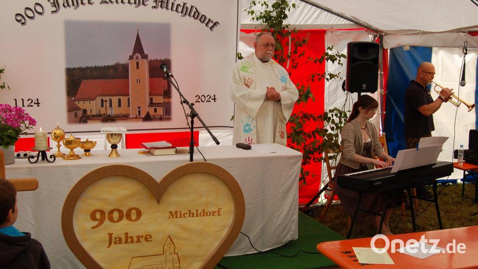 Ein großes Transparent und ein Herz mit Bild und Inschrift zierten den Altar im Zelt beim Festgottesdienst zum Jubiläum „900 Jahre Pfarrei Michldorf“ mit Pfarrer Alfons Forster. Paulina Winter und Gernot Völkl sorgten für die Musik. Bild: grm