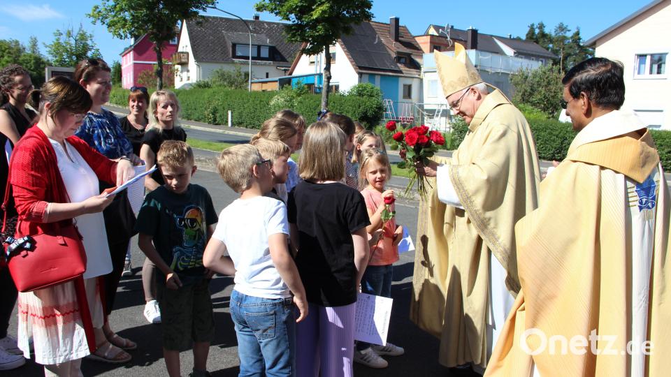 Der Kindersingkreis begrüßt Bischof Rudolf Voderholzer und überreicht ihm eine Rose. Rechts Pfarrer Augustin Lobo. Bild: lep