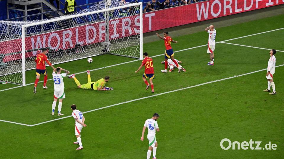 Italiens Torhüter Gianluigi Donnarumma liegt nach dem Gegentor am Boden. Die Spanier jubeln, während die Italiener enttäuscht auf dem Platz stehen. Bild: Julian Stratenschulte/dpa