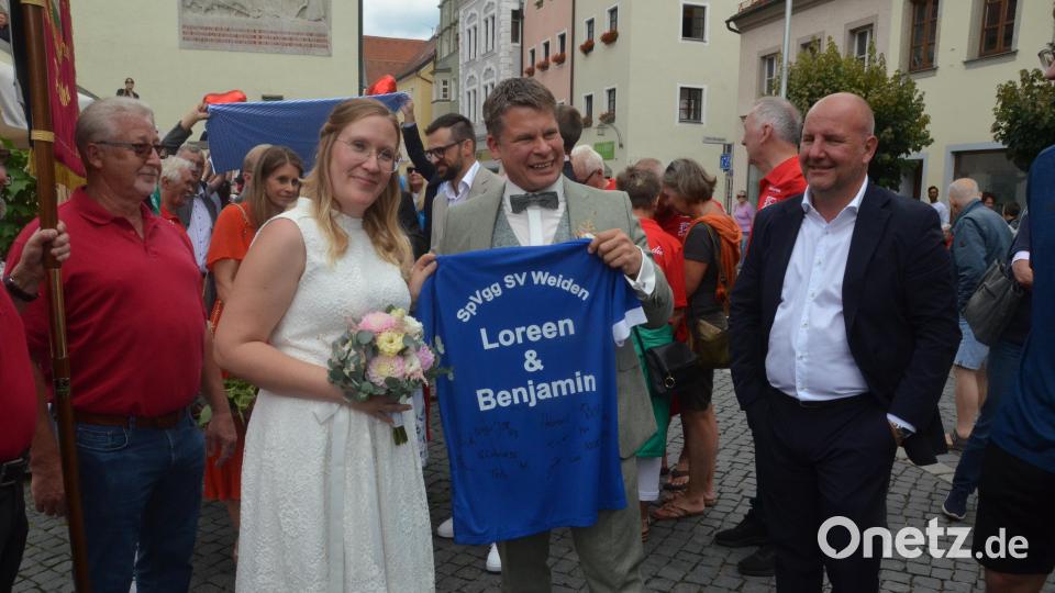 Das Hochzeitspaar Loreen und Benjamin Zeitler bekommt von SpVgg-SV-Weiden-Präsident Michael Kurz ein passendes Trikot. Bild: Kunz