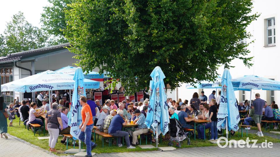Unter Sonnenschirmen genießen die Besucher das Kirchweihfest am Pfarrheim. Bild: fvo