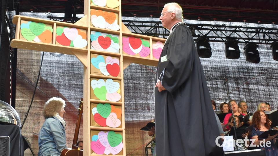 Regionalbischof Klaus Stiegler betrachtet das Kreuz mit den vielen bunten Herzen, auf dem notiert ist, was die Menschen unter &quot;Heimat&quot; verstehen. Bild: rgr