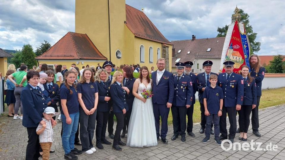 Die Oberlinder Feuerwehrleute nehmen das Brautpaar Michael und Antonia Kellner nach der Trauung in der St.-Thomas-Kirche in ihre Mitte und gratulieren herzlich. Bild: dob