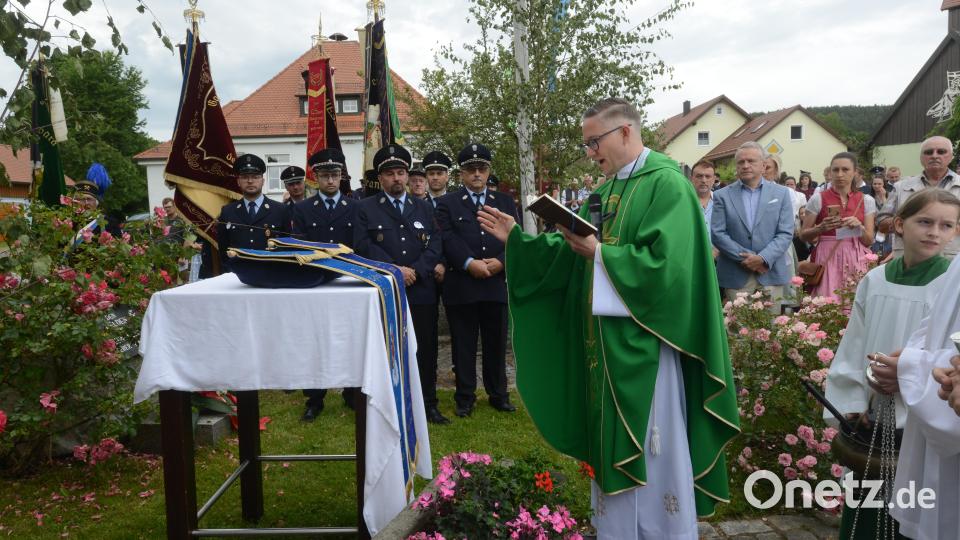Stadtpfarrer Adam Karolzak segnet im Festgottesdienst vor der Barbara-Kapelle die Erinnerungsbänder für die Feuerwehren Hagendorf und Reinhardsireth Bild: bey