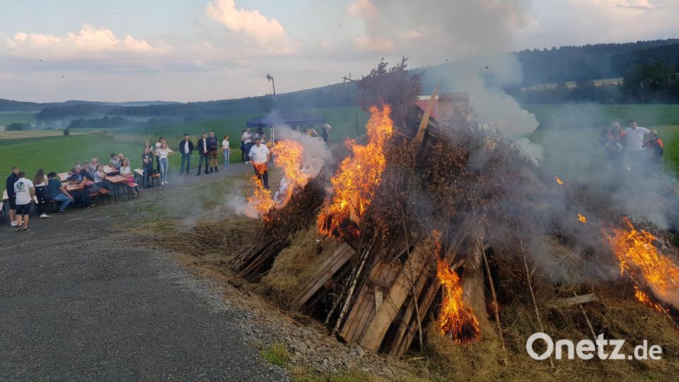 Die Landjugend Tröbes bleibt dem Brauchtum treu und entzündet das Johannisfeuer auf der Busl-Höhe über Tröbes, das Pfarrer Udo Klösel gesegnet hatte. Bild: Peter Garreiss