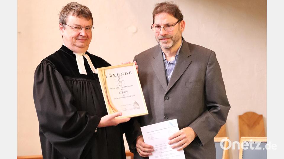 Stadtpfarrer Dr. Roland Kurz überreicht Dekanatskantor Gerd Hennecke (von links) die Urkunde des Kirchenmusikerverbandes zum 40-jährigen Dienstjubiläum. Bild: cog