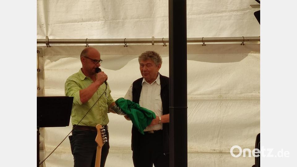 TSV-Vorsitzender Richard Zeiler überreicht Pfarrer Ambros Trummer ein TSV-T-Shirt und eine Jacke. Bild: hme