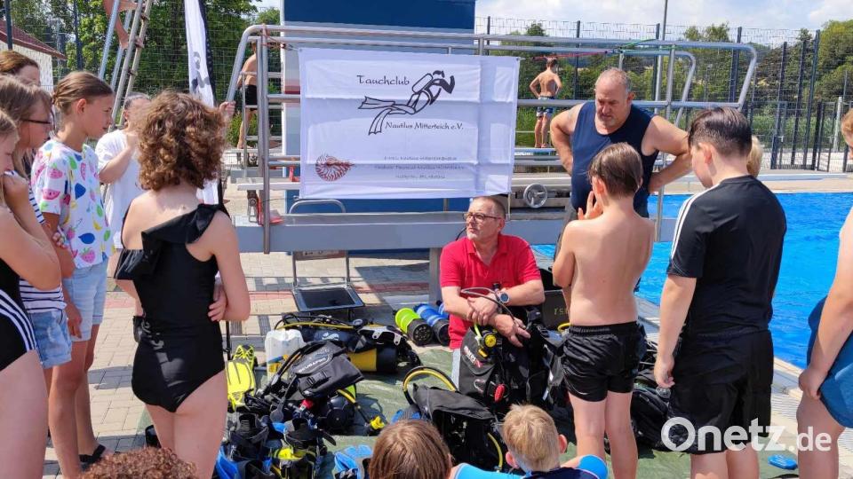 Tauchclub-Vorsitzender Arno Wirnitzer und Tauchlehrer Harald Ullmann (hinten von rechts) erläuterten den Kindern zunächst Verhaltensregeln unter Wasser sowie die Tauchausrüstung. Bild: Thomas Neufeld/exb