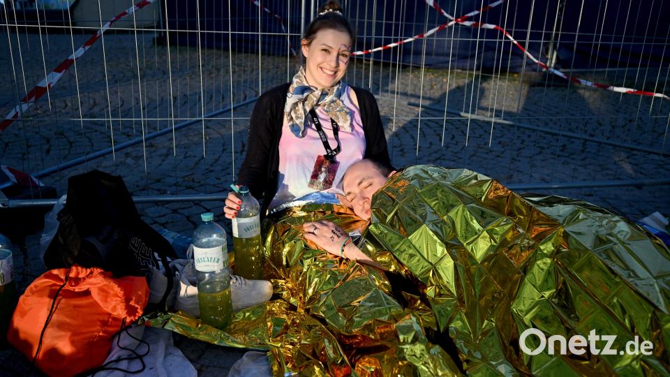 Die Fans Elisa und Renee liegen im Olympiapark vor dem Eingang zum Olympiastadion und haben sich in eine Rettungsdecke gehüllt. Bild: Felix Hörhager /dpa