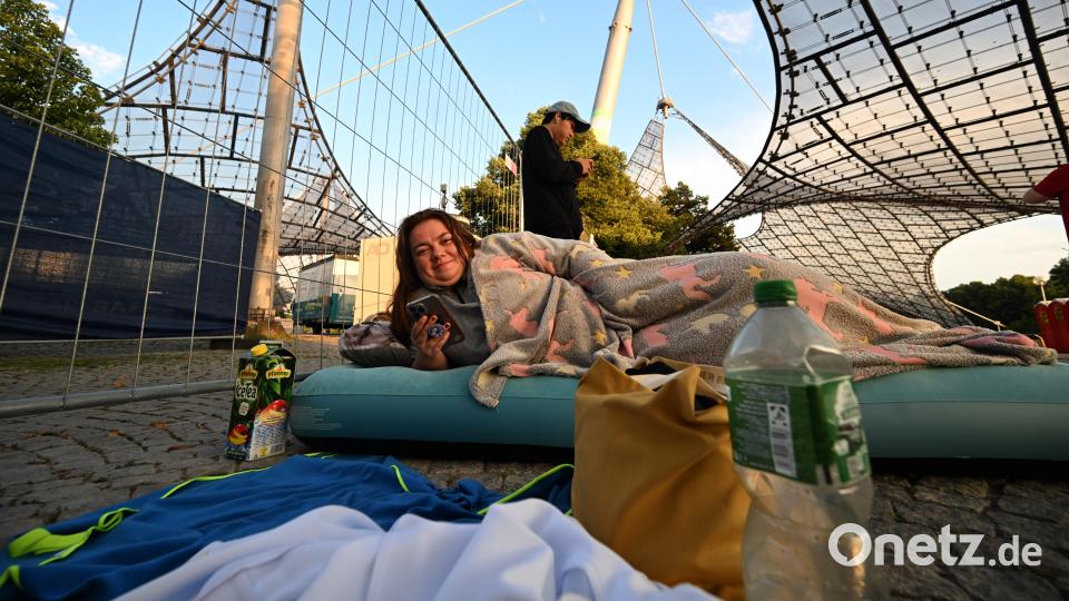 Viviane liegt im Olympiapark vor dem Eingang zum Olympiastadion auf einer Luftmatratze und hat sich in eine Decke gewickelt. Bild: Felix Hörhager/dpa