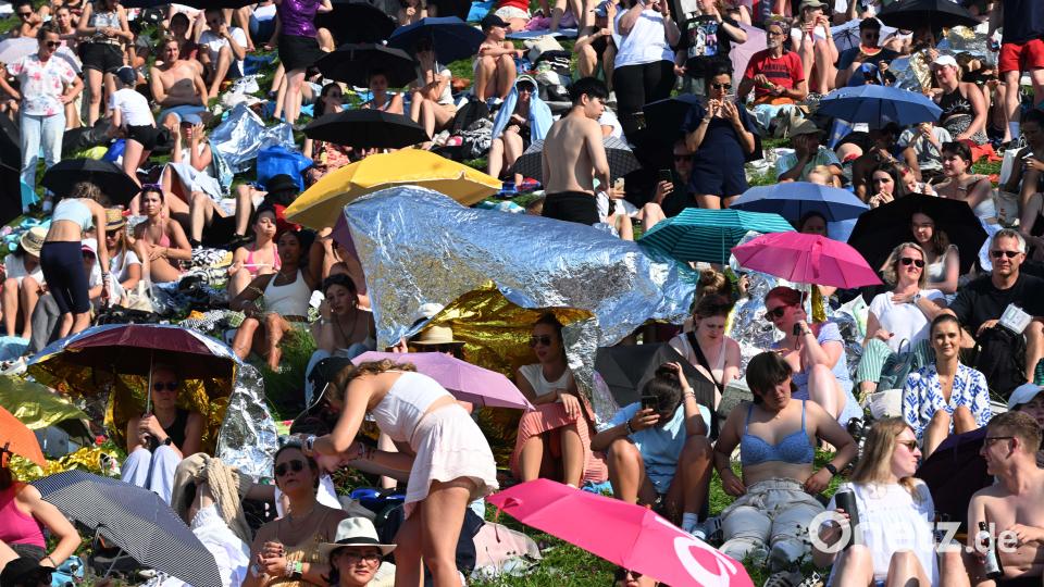 Fans sitzen bei Sonnenschein auf dem Olympiaberg und warten auf den Beginn des Taylor Swift Konzert. Bild: Felix Hörhager /dpa