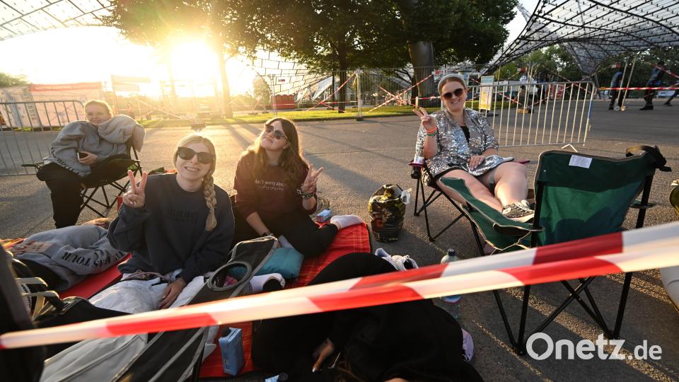 Die Fans Laura (l-r), Miriam und Annemarie sitzen im Olympiapark vor dem Eingang zum Olympiastadion und gestikulieren zum Fotografen. Bild: Felix Hörhager/dpa