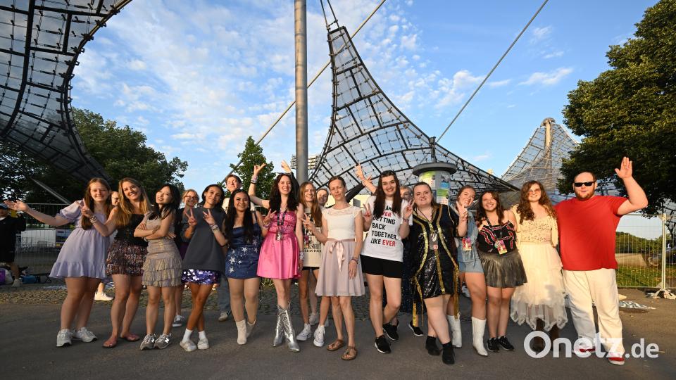 Fans stehen im Olympiapark vor dem Eingang zum Olympiastadion und winken dem Fotografen. Bild: Felix Hörhager/dpa