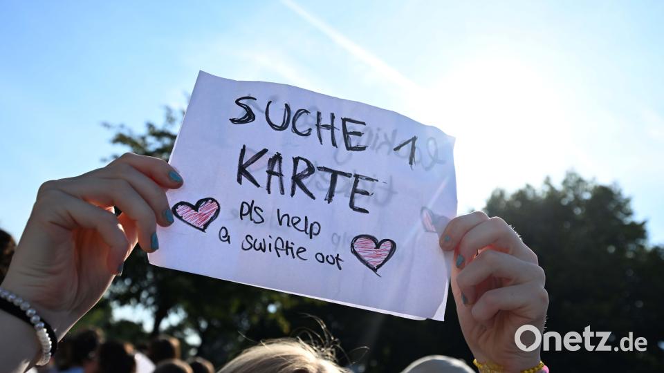 Ein weiblicher Taylor Swift Fan hält vor dem Olympiastadion einen Zettel mit der Aufschrift "Suche 1 Karte" hoch. Bild: Felix Hörhager /dpa