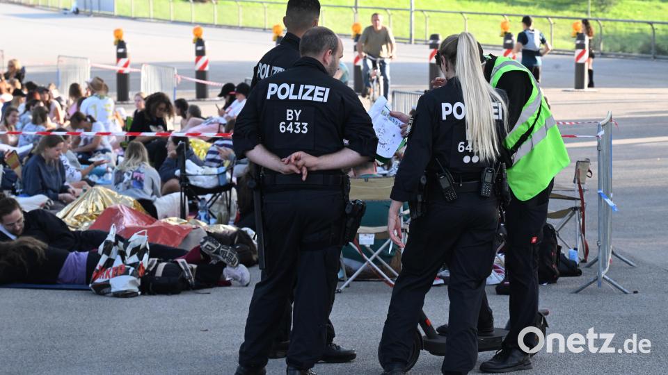 Polizisten und Ordner stehen im Olympiapark in den frühen Morgenstunden vor dem Eingang zum Olympiastadion, an dem eine Schlange Fans wartet (hinten). Bild: Felix Hörhager /dpa