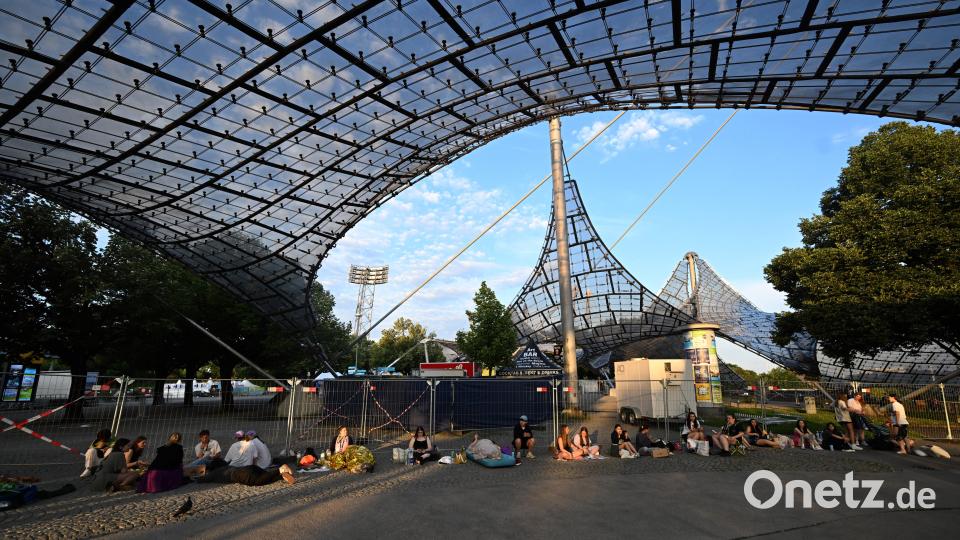 Fans sitzen im Olympiapark vor dem Eingang zum Olympiastadion. Am Samstag findet dort das erste von zwei Konzerten in München von Taylor Swift im Rahmen ihrer «The Eras Tour» statt. Bild: Felix Hörhager/dpa