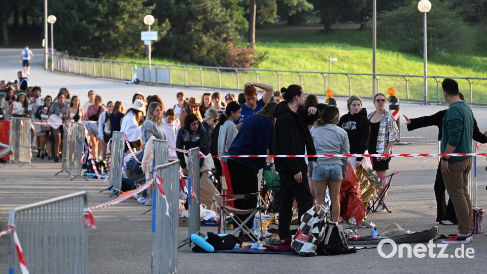 Fans stehen und warten im Olympiapark vor dem Eingang zum Olympiastadion. Bild: Felix Hörhager /dpa