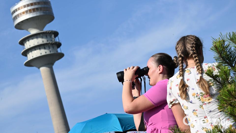 Eva schaut mit einem Fernglas vom Olympiaberg in Richtung Olympiastadion, im Hintergrund ist der Olympiaturm zu sehen. Bild: Felix Hörhager /dpa