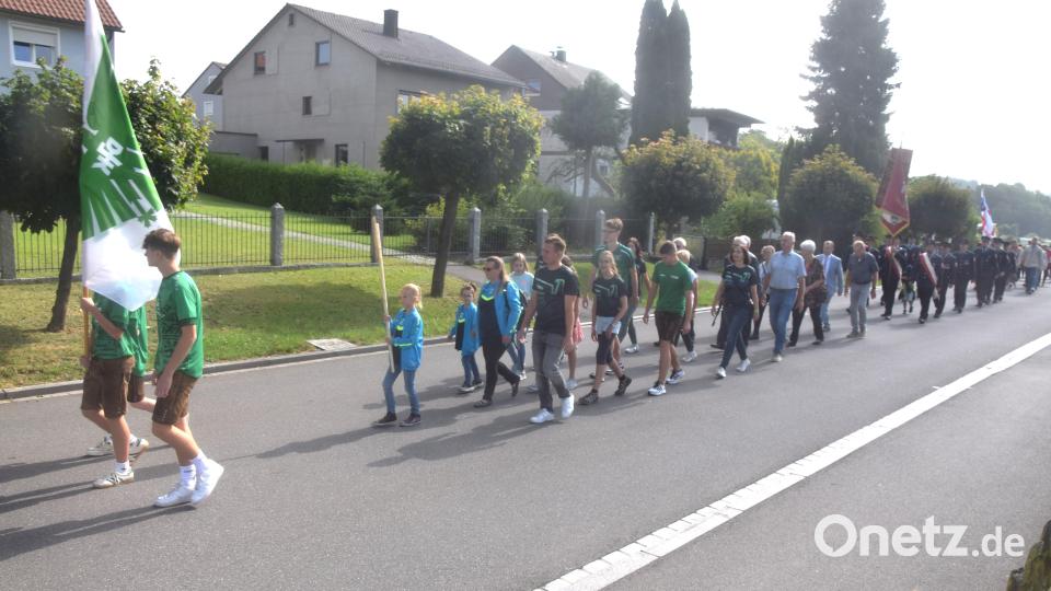Hinter der DJK-Fahne marschieren die Mitglieder der DJK Neuhaus beim Festzug von der Kirche zum Sportgelände zusammen mit den weiteren Neuhauser Vereinen. Bild: fz