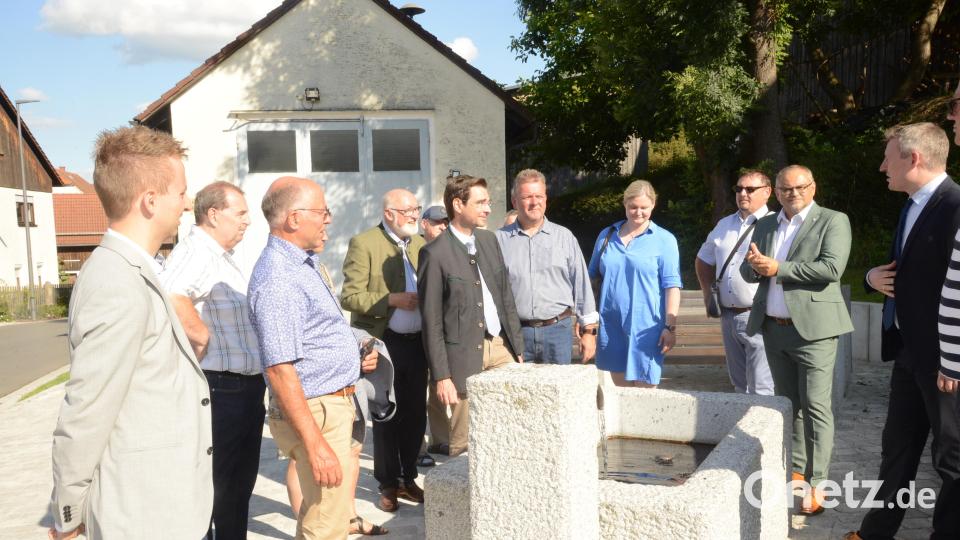 Der Rundgang mit Bürgermeister Johannes Kett (rechts) führte die Ehrengäste auch an den Mittelpunkt Wilchenreuths mit dem Feuierwehrhaus (im Hintergrund) und an den Dorfbrunnen mit der Sitzgarnitur. Bild: bey