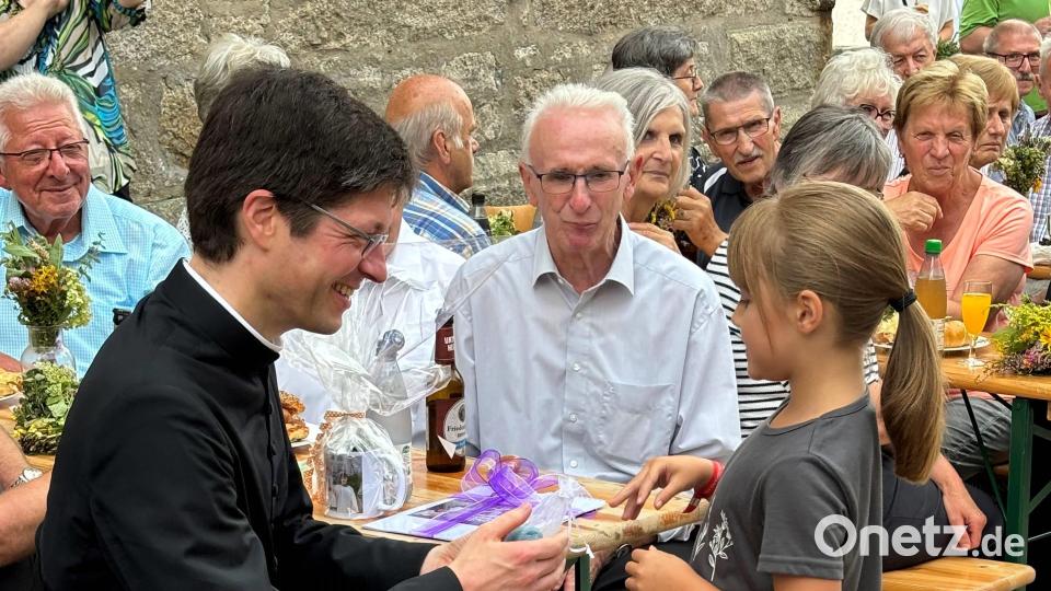 Pfarrer Gierl bekommt von der Ministrantin Anna Eismann ein Geschenk überreicht Bild: cro