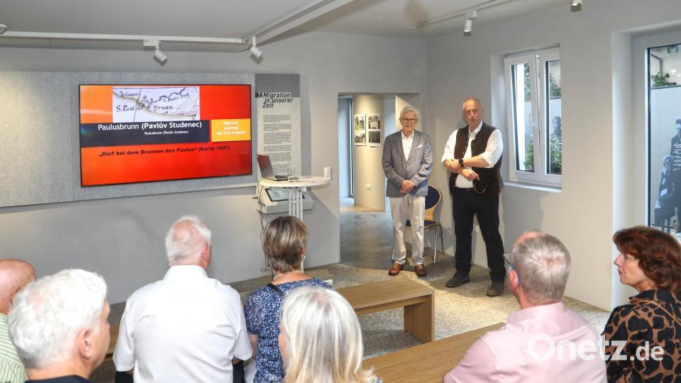 Seit Kurzem ist im Museum Flucht – Vertreibung – Ankommen eine Ausstellung über das verschwundene Dorf Paulusbrunn zu sehen. Bei der Ausstellungseröffnung referierte Rainer Christoph (stehend, links). Museumsleiter Jochen Neumann (stehend, rechts) begrüßte ihn und die Gäste. Bild: Jochen Neumann/exb