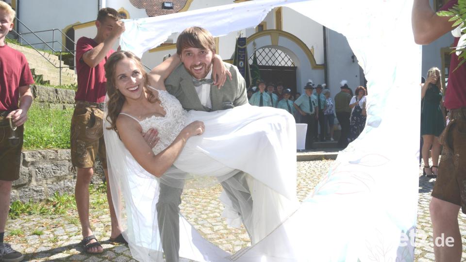 Zuerst musste das Brautpaar bei der Katholischen Jugend Neudorf ein Herz ausschneiden, dann durfte Bräutigam David Piehler seine Braut Luisa durch das Herz tragen. Bild: bey