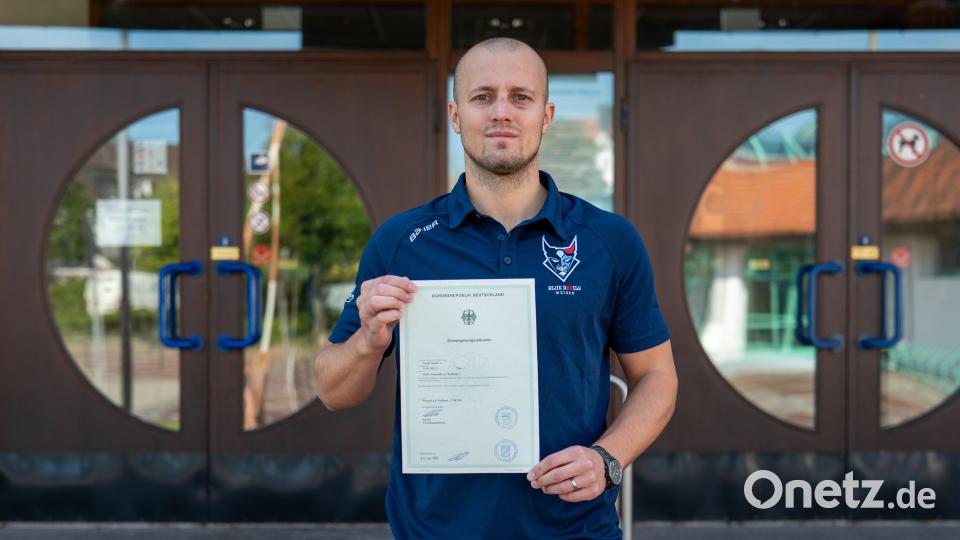 Tomas Rubes präsentiert seine Einbürgerungsurkunde vor der Hans-Schröpf-Arena. Bild: Christian Kaminsky/exb