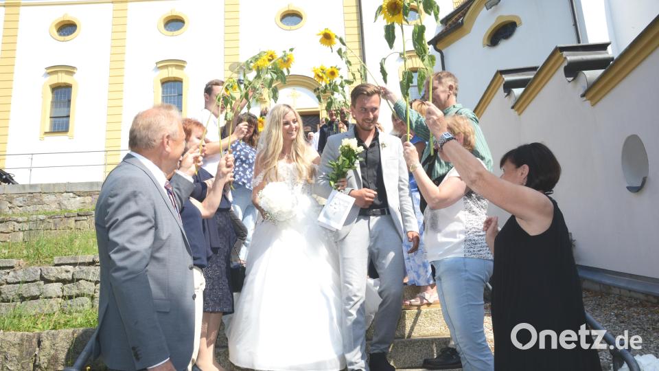 Thomas und Magdalena Wagner durchschreiten nach der Trauung in der Kreuzbergkirche Pleystein ein Spalier aus Sonnenblumen. Bild: bey