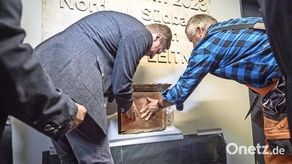 Und rein mit dem Ding: Landrat Wiedemann muss als Erster zur Kelle greifen, um die neue Zeitkapsel einzumauern. Bild: Eric Waha/fph