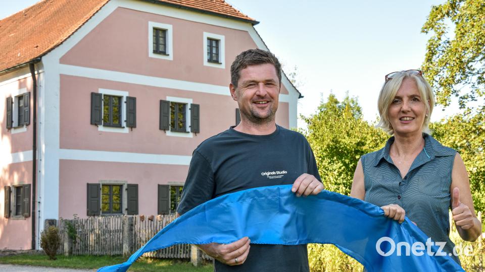 Kulturführerin Tina Seng hatte die Idee zum &quot;Tag des Wassers&quot; in Theuern, Tobias Birner vom Heimatverein Theuern unterstützt sie bei der Umsetzung. Blaue Fahnen zeigen den Besuchern den Weg zu den Angeboten rund um die alte Mühle (im Hintergrund). Bild: Stephan Huber