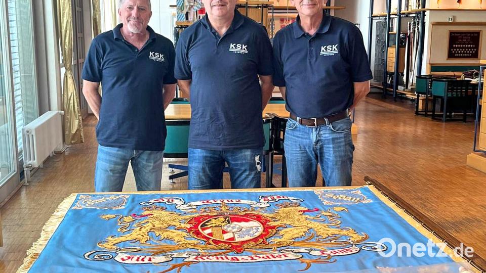 Die restaurierte 120 Jahre alte Fahne wird von Vorsitzenden Roland Veigl, Stefan Reichl und Markus Popp (von rechts) bei Fahnen Kössinger in Schierling abgeholt. Bild: whü