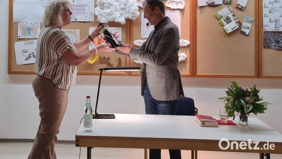 Christine Rupprecht bedankt sich bei Autor Horst Eckert mit einer Flasche Wein, die den Segensspruch der Jahreslosung aufgedruckt hatte. Bild: rpp