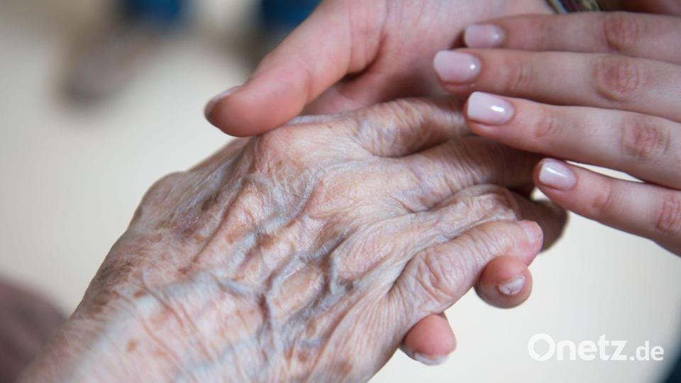 Alt und Jung: Eine Pflegerin hält die Hand einer Bewohnerin im Seniorenzentrum. Aber wie lange kann dieses Versorgungssystem noch funktionieren? (Symbolbild) Bild: Christophe Gateau/dpa