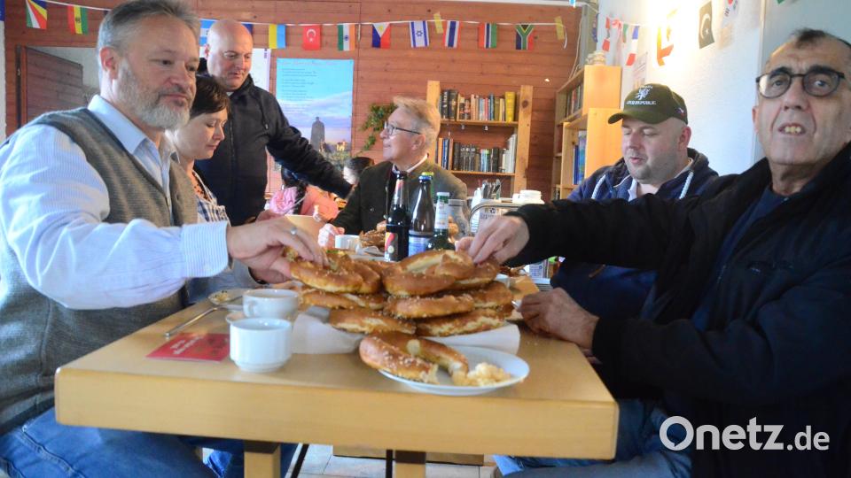 Zu einer zünftigen bayerischen Brotzeit gehören frische Brezen. Die lassen sich beim Interkulturellen Oktoberfest auch Stadtrat Ali Zant (links) und Bürgermeister Reinhold Wildenauer (Mitte, sitzend) schmecken. Bild: Kunz
