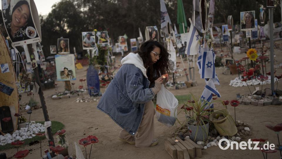 Eine Frau zündet am jüdischen Feiertag Simchat Tora, der im hebräischen Kalender ein Jahr nach dem Anschlag begangen wird, in der Nähe des Kibbuz Re&#039;im im Süden Israels nahe dem Gazastreifen Kerzen auf dem Gelände des Nova-Musikfestivals an, bei dem Hunderte von Feiernden von der Hamas getötet oder entführt wurden. Bild: Maya Alleruzzo/dpa