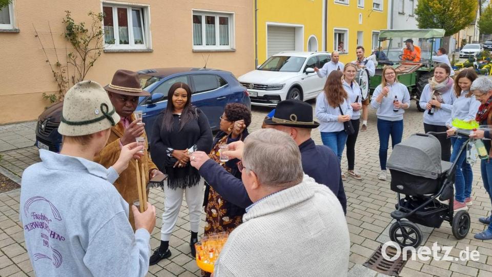 Diakon Ndudi Kelechi Izuagba (2. von links) musste die hochprozentige Stärkung aus den Händen von Altbürgermeister Sepp Reindl (5. von links) erstmal grünlich in Augenschein nehmen, bevor er sie genoss. Bild: nag