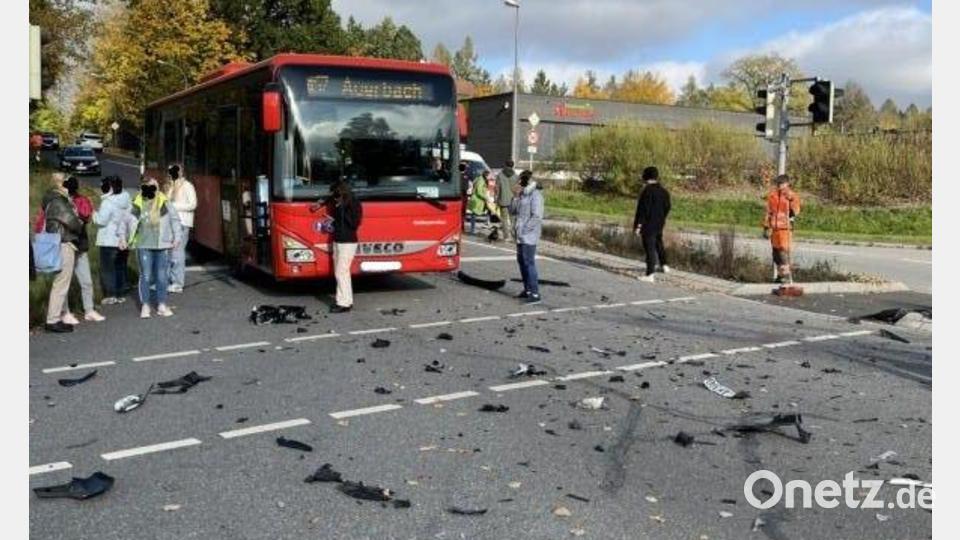 Die unverletzt gebliebenen Fahrgäste des Linienbusses stehen auf der Straße und schauen sich das Trümmerfeld auf der Krötenseekreuzung an, das entstanden ist, nachdem ein Peugeot mit Wucht gegen die linke Seite des Busses geschleudert wurde. Bild: Polizeiinspektion Sulzbach-Rosenberg
