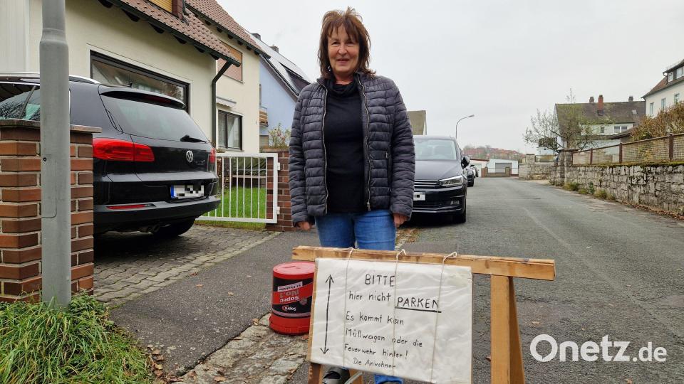 Christine Humbs zeigt ein von den genervten Anwohnern der oft zugeparkten Albert-Schweitzer-Straße selbstgemachtes Hinweisplakat: "Bitte hier nicht parken. Es kommt kein Müllwagen oder die Feuerwehr hinter!" Bild: Tobias Gräf