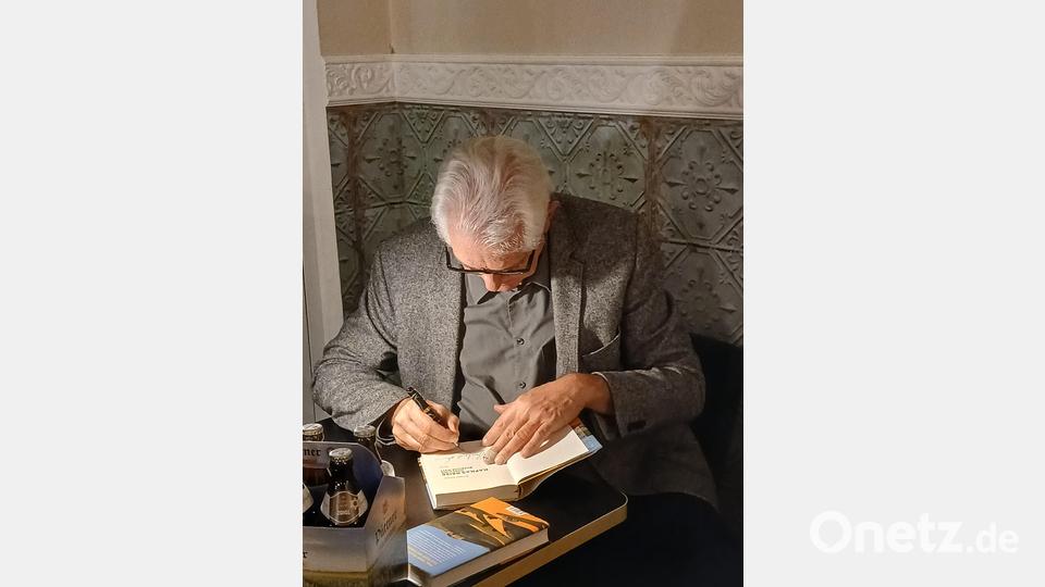 Bernhard Setzwein signiert ein Buch nach der Lesung aus seinem neuen Roman „Kafkas Reise durch die bucklige Welt“ in Pressath. Bild: Heiner Brückner