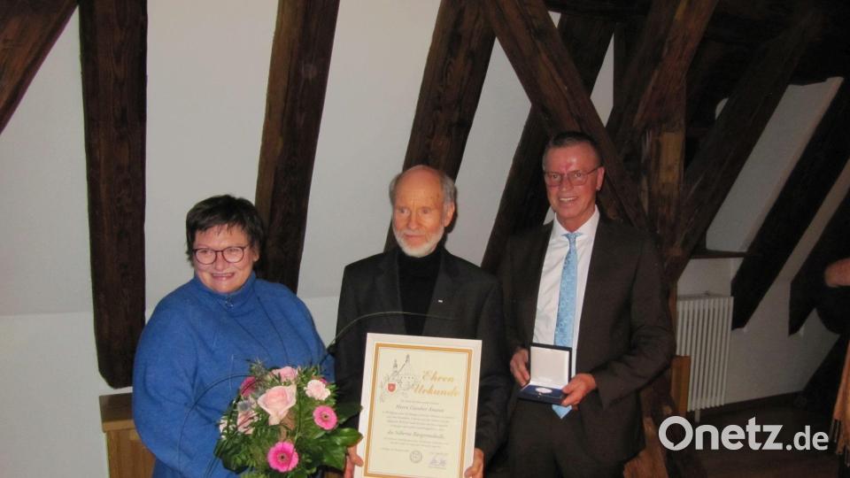 Bürgermeister Herrmann Falk (rechts) überreicht an Günther Amann die silberne Bürgermedaille der Stadt Hirschau. Dessen Lebensgefährtin Christine Schwager erhält einen Blumenstrauß. Bild: fg