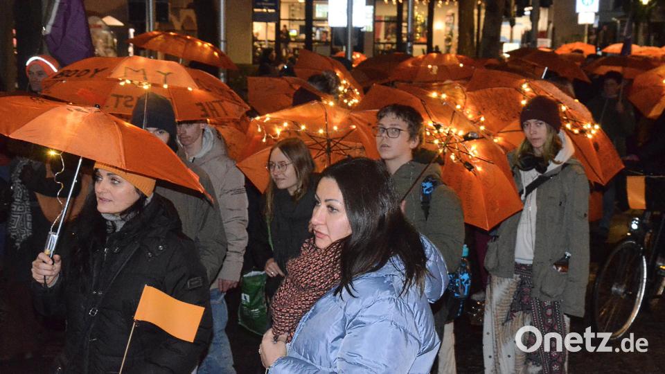 Mit orangefarbenen Regenschirmen zogen die Teilnehmerinnen und Teilnehmer des Schweigemarschs mit kurzen Stopps für Statements durch die Innenstadt. Bild: Kunz