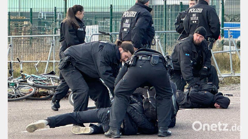 Polizisten halten Demonstranten am Boden fest. Sie hatten zuvor versucht mit Fahrrädern Richtung Veranstaltungshalle vorzudringen. Bild: Jörg Ratzsch/dpa