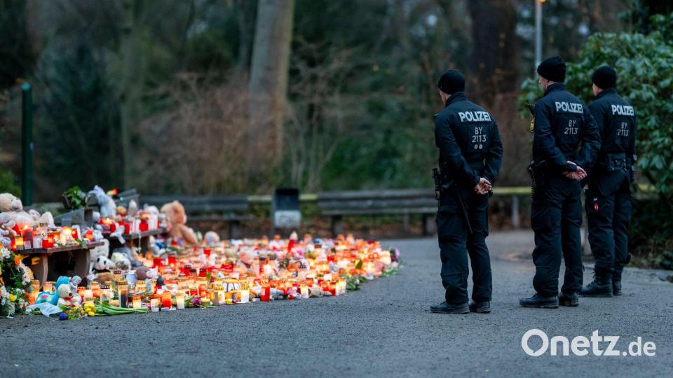 Mehrere Polizisten stehen vor der Ansammlung an Kerzen, Blumen und Kuscheltieren im Park. Bild: Jacob Schröter/dpa