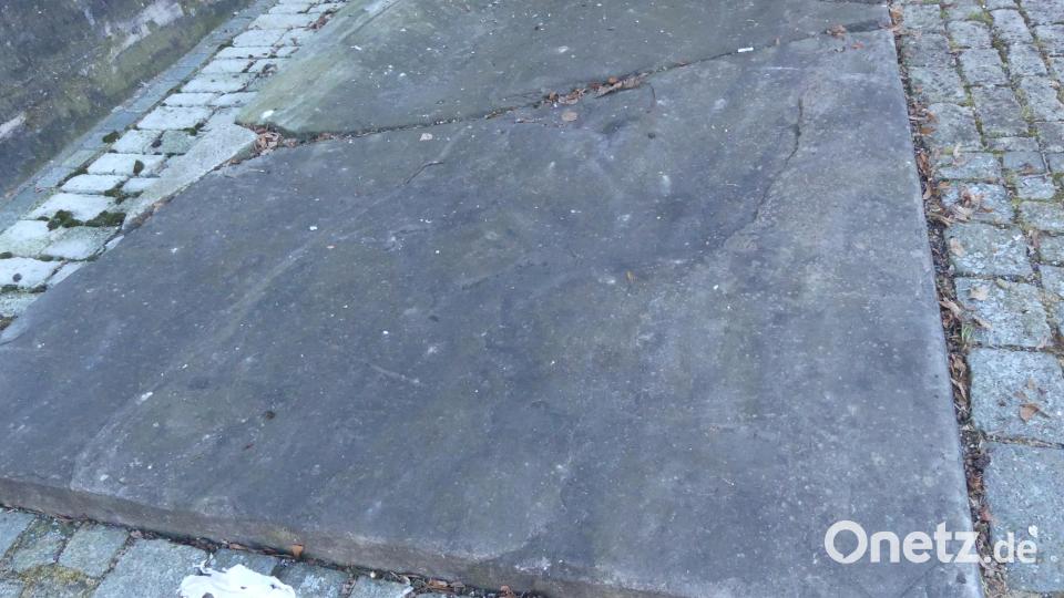 Der Grabplatte neben der Pfarrkirche St. Laurentius mit Wappenrest (rechts unten) schreibt Roman Schneider ein Alter von 500 Jahren zu. Bild: rn